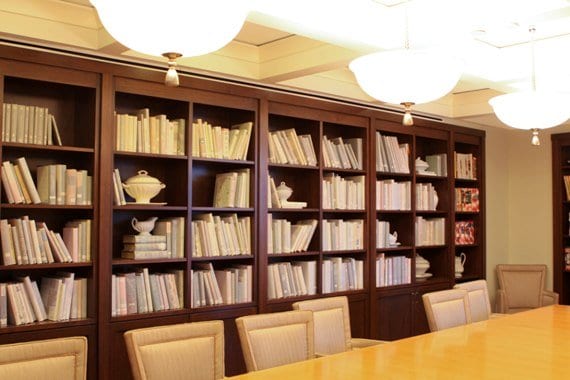 A Large Bookshelf Behind a Long Wooden Dining Table