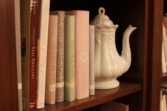 A Close-Up of Books and a Tea Kettle on a Dark Wooden Shelf