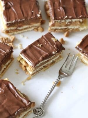 A few Chocolate Peanut Butter and Caramel Bars with a Chocolate Topping and layers of caramel with a fork.