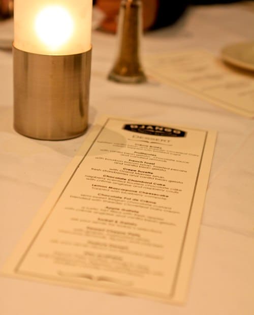 A Close-Up Image of the D'Jango Dinner Menu Next to a Candle