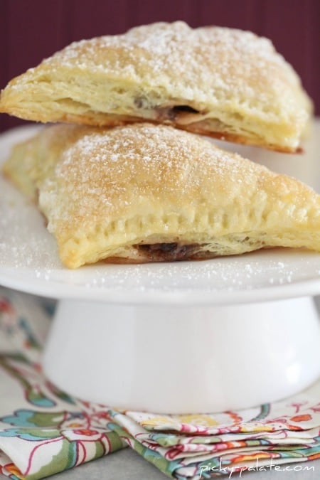 Triangular turnovers filled with nutella and marshmallow on a cake stand.