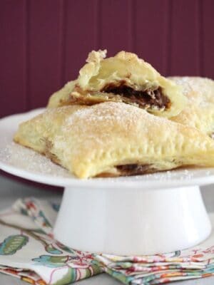 Triangular turnovers filled with nutella and marshmallow on a cake stand.