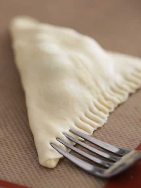 A fork is used to crimp the edge of a turnover pastry.