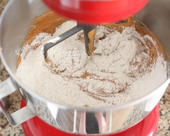 Flour is added into a stand mixer with peanut butter cookie ingredients.
