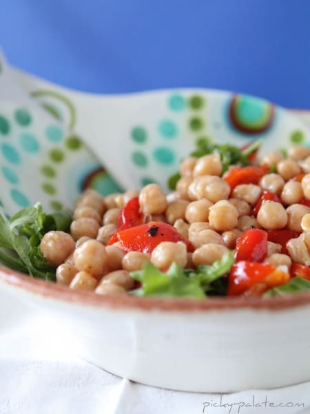 Chickpea, sweet pepper and arugula salad in a white bowl.