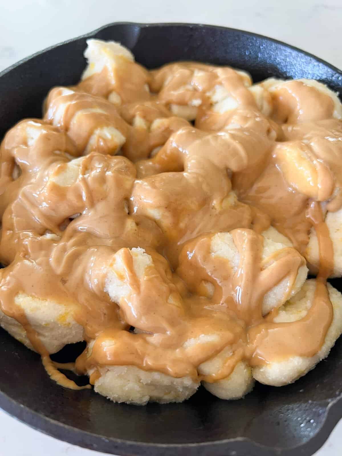 peanut butter drizzled over monkey bread in skillet