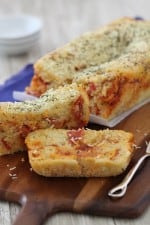A Loaf of Cheesy Pepperoni Pizza Quick Bread with Two Slices Cut Out