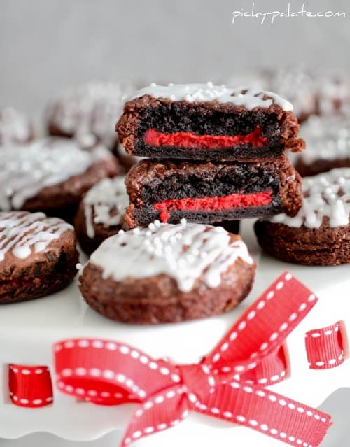Brownie covered Oreos stacked on a white plate with a red ribbon.