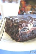 A Cookies and Cream Swirled Brownie topped with a Chocolate and Peanut Butter Ganache with a fork and glass of milk.