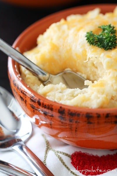 A Spoon Digging into a Bowl of Smoky & Cheesy Buttermilk Baked Mashed Potatoes