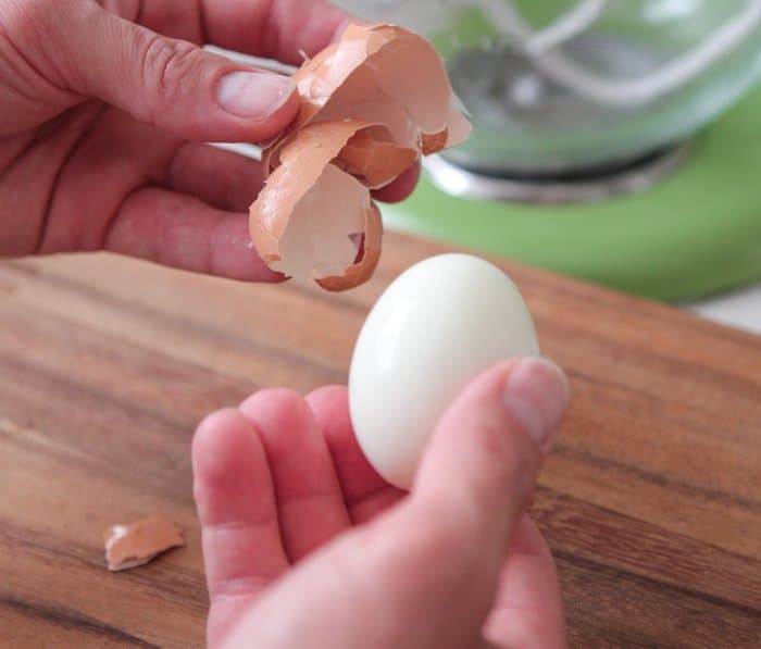 Hands removing the shell from a boiled egg