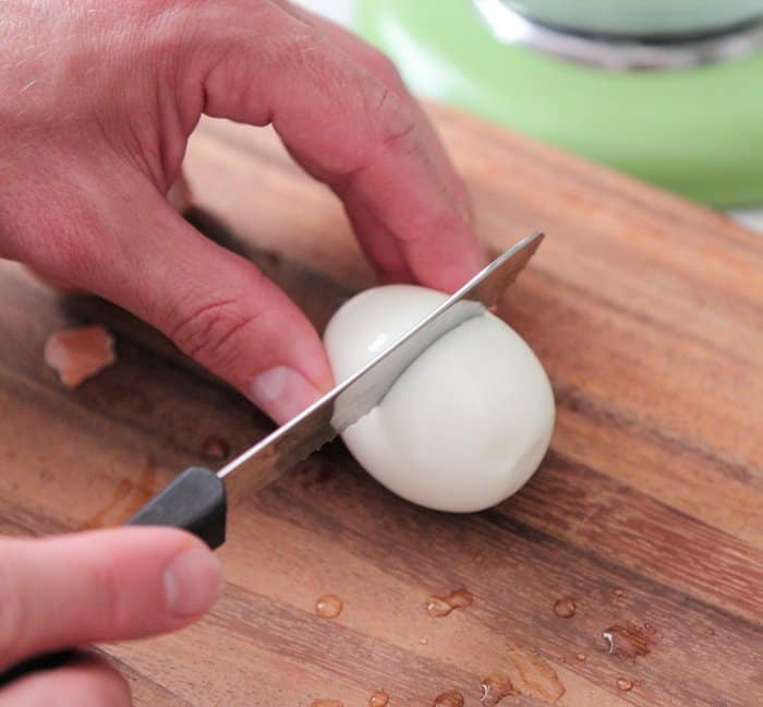 Hands cutting a hard boiled egg in half
