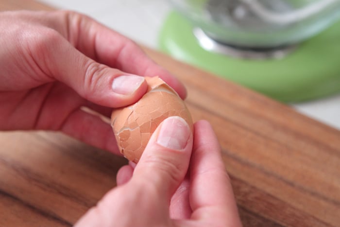Hands peeling an egg