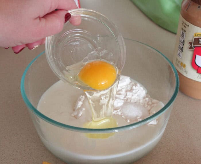 adding egg to mixing bowl for homemade pancakes