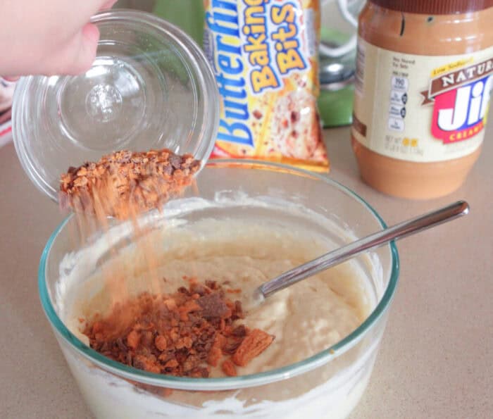 adding crushed butterfinger to mixing bowl for homemade pancakes