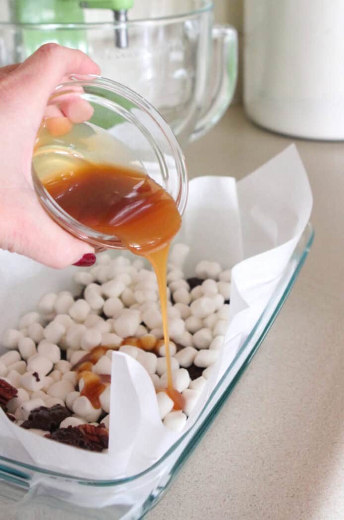 drizzling caramel sauce over marshmallow layer of brownies