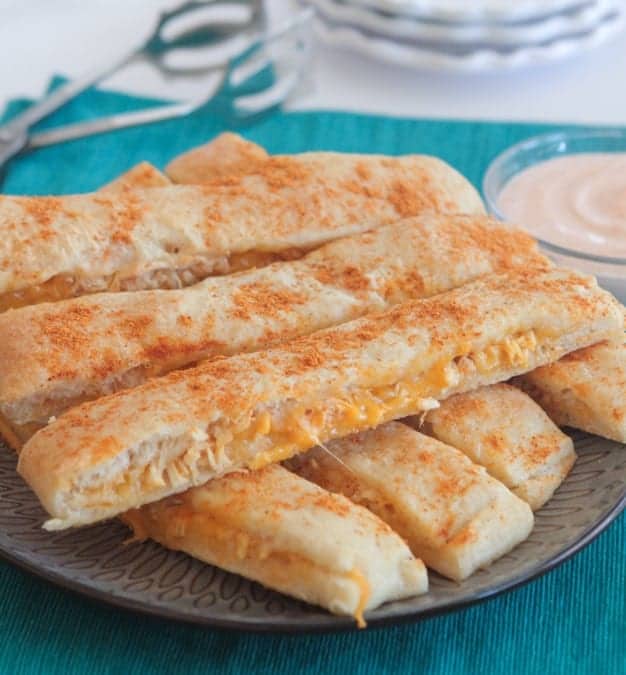 Cheesy chicken taco breadsticks stacked on a plate.