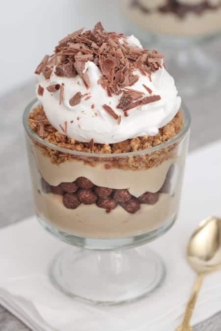 A cup with chocolate and peanut butter pie parfait topped with whipped cream and chocolate shavings.