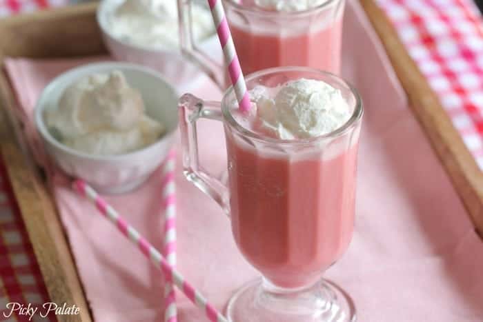 Two pink strawberry milk slushies side-by-side, topped with ice cream.