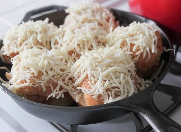 Ham and cheese skillet sandwiches topped with shredded cheese in a cast iron skillet.
