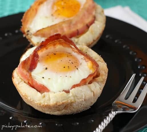 Bacon and cheese Egg McMuffin cups on a black plate next to a fork.