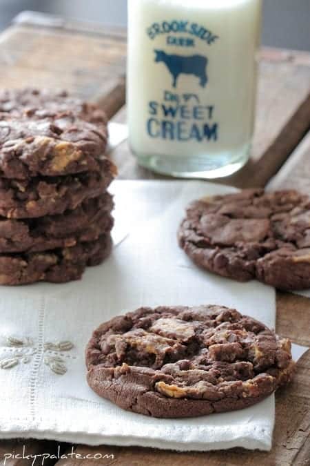 Reese's Peanut Butter Chunk chocolate cake mix cookies in a stack, next to scattered cookies.