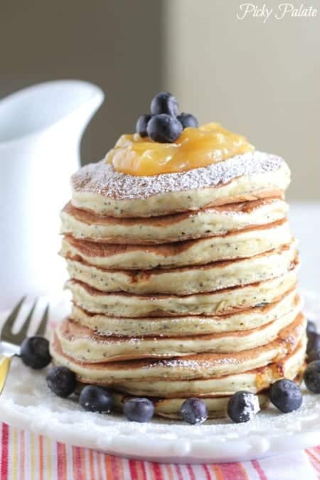 A stack of lemon poppyseed ricotta pancakes topped with blueberries.
