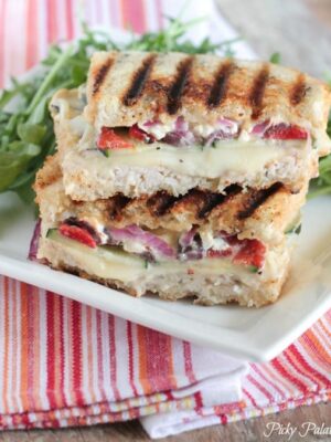 Two halves of a Loaded Turkey and Hummus Panini stacked on a plate.