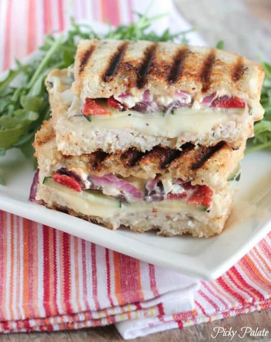 Two halves of a Loaded Turkey and Hummus Panini stacked on a plate.