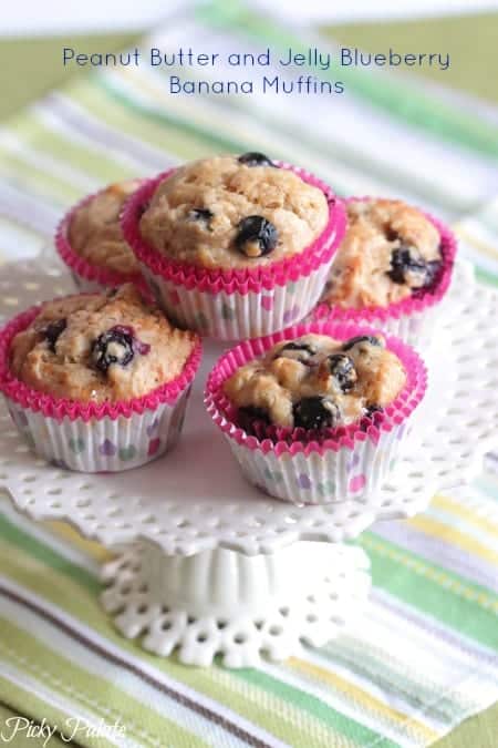 Peanut Butter and Jelly Blueberry Banana Muffins stacked on a cake stand.