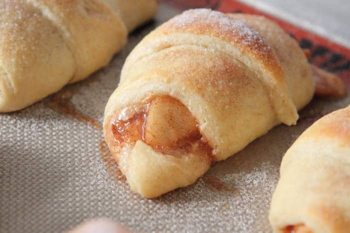 Roasted apples and peanut butter crescent rolls on a baking sheet.