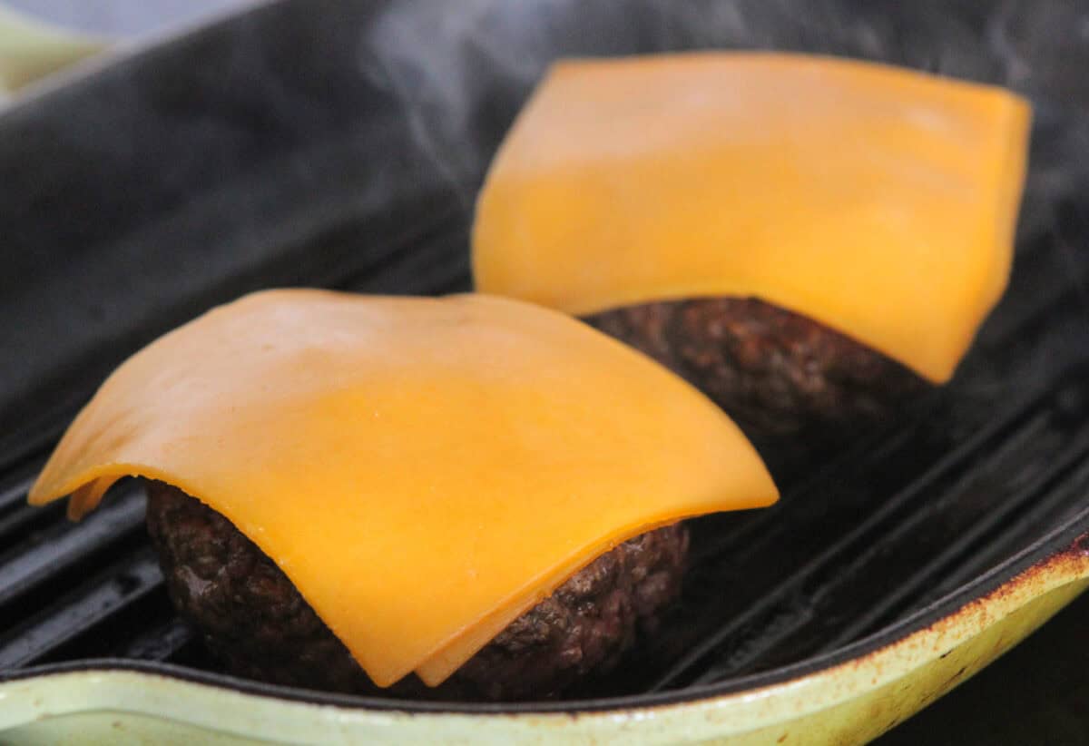 cheese added to burgers on grill