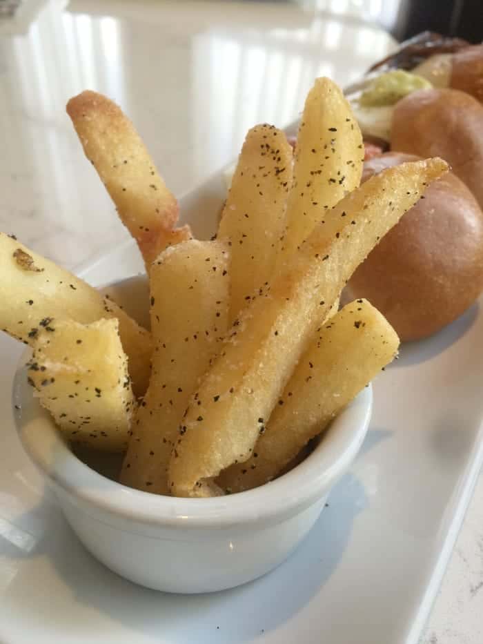 Seasoned French Fries in a Small White Bowl Next to Three Breakfast Sandwiches