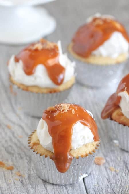 Four Caramel Cupcakes with Silver Liners on a Gray Picnic Table