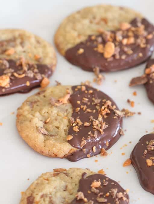 Chocolate Dipped Cookies with Butterfinger Bits Arranged on a White Surface