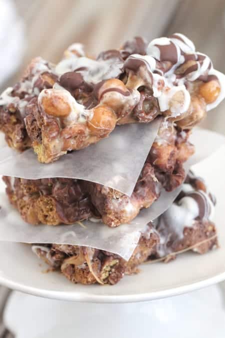 Three Chocolate Peanut Butter Crunch Bars Stacked Between Pieces of Parchment Paper