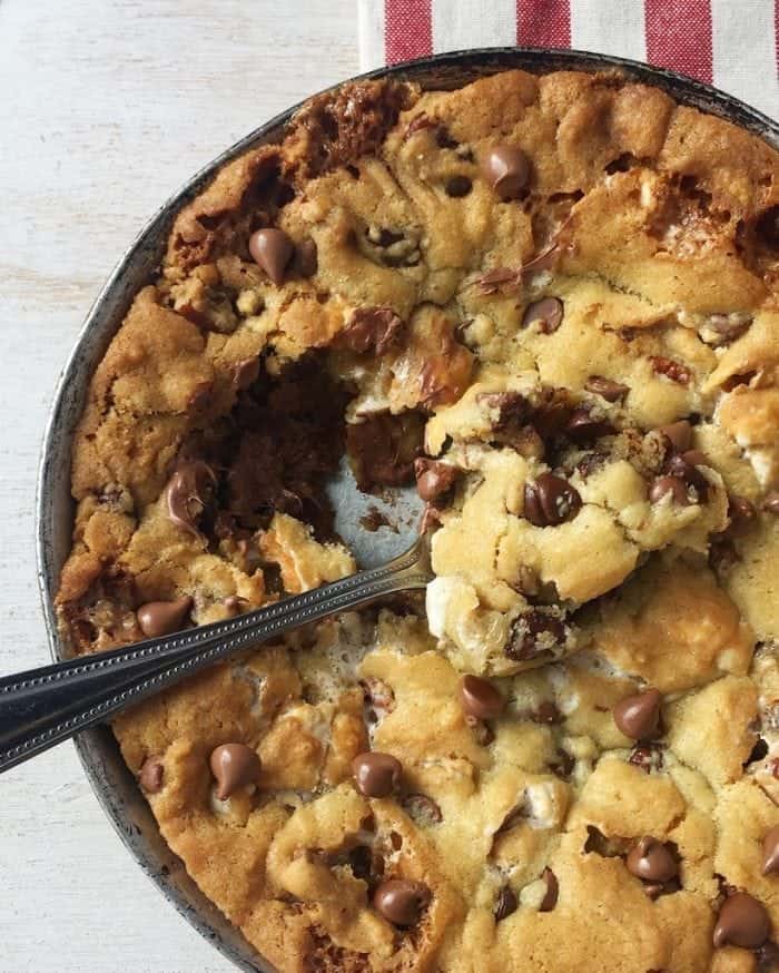 A Kitchen Sink Skillet Cookie with a Spoon Scooping Out a Bite
