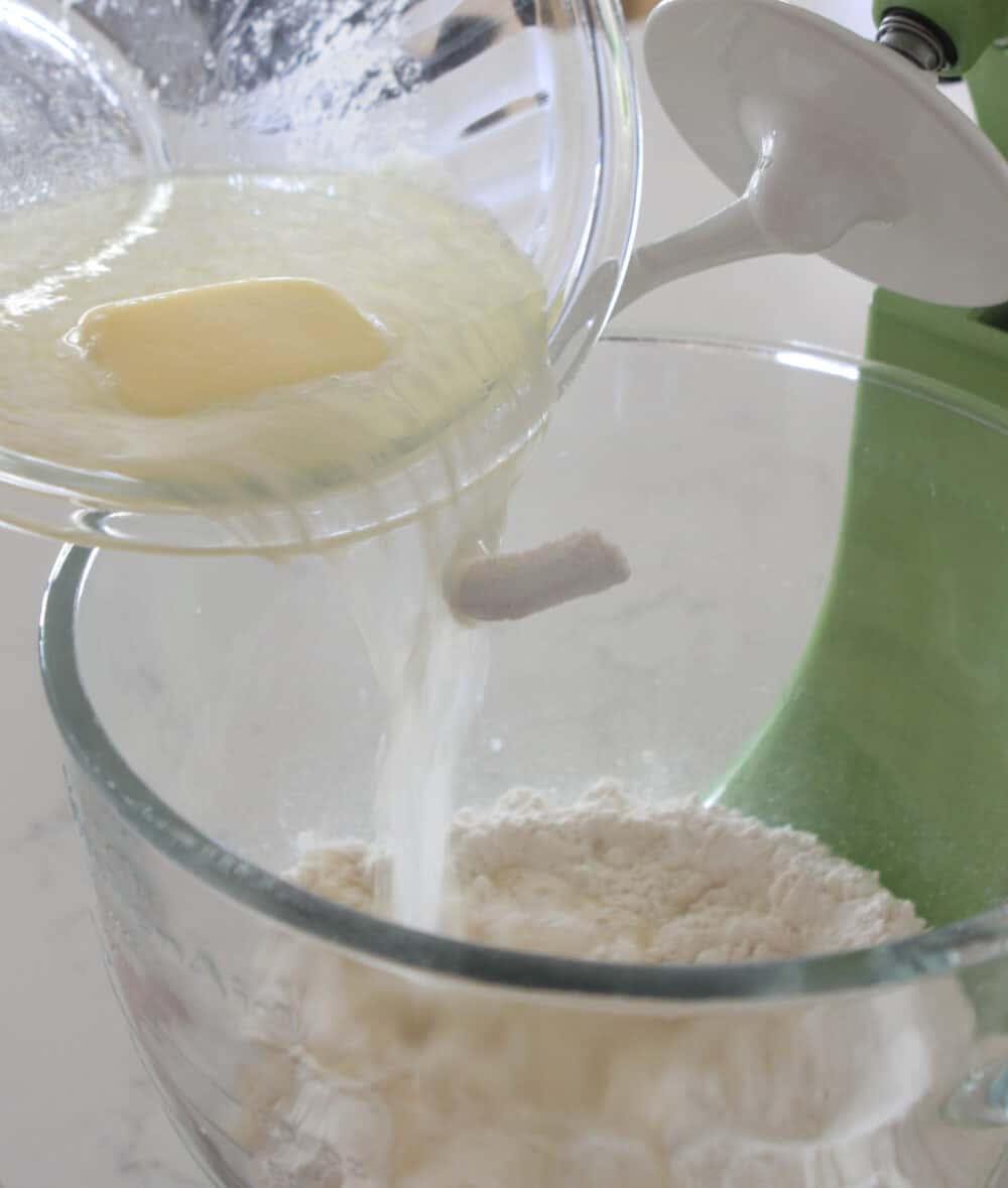 pouring warm butter into sweet rolls mixing bowl