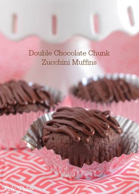 Double chocolate zucchini muffins in cupcake liners, drizzled with chocolate.