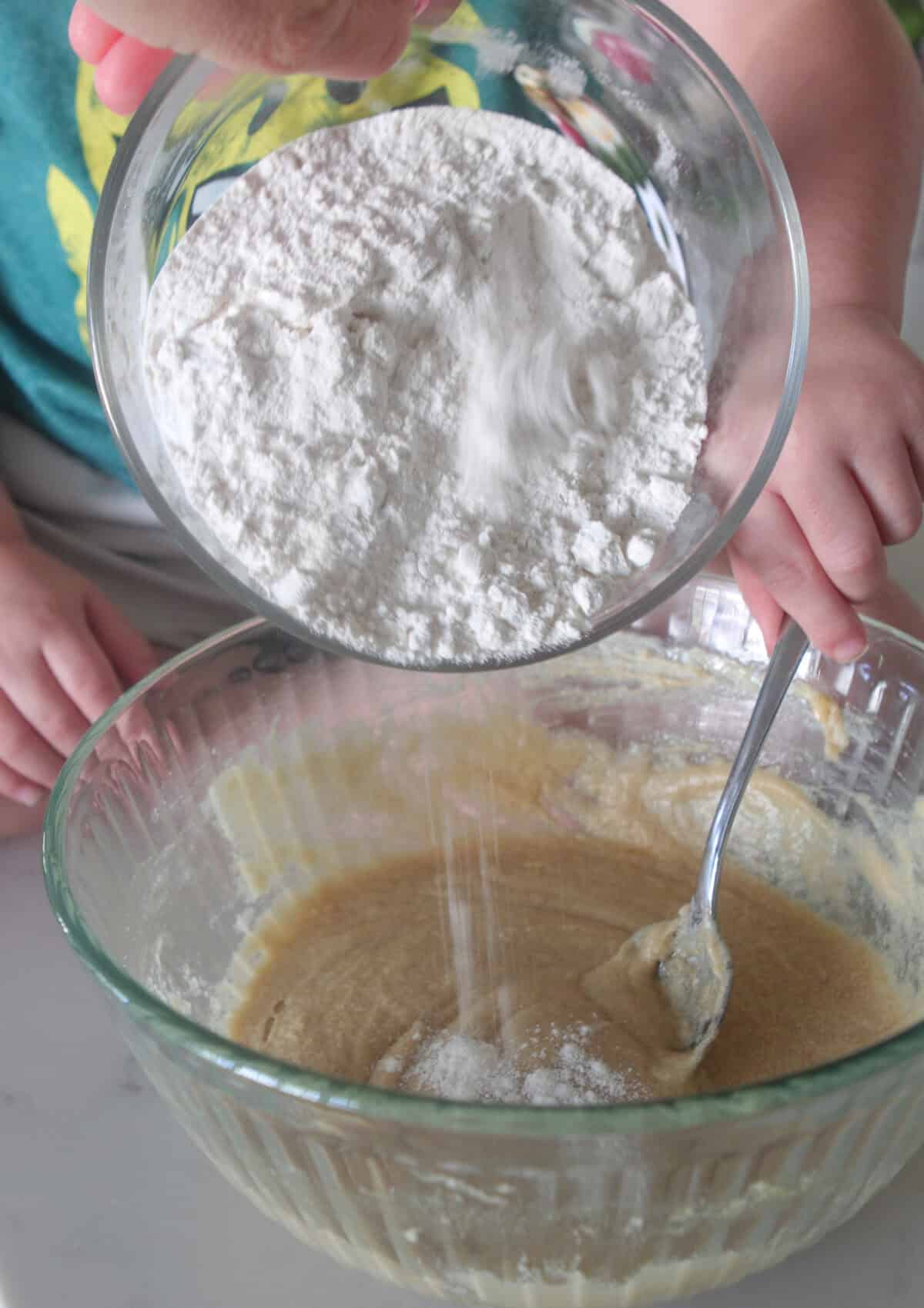 adding dry ingredients to cookie dough mixing bowl