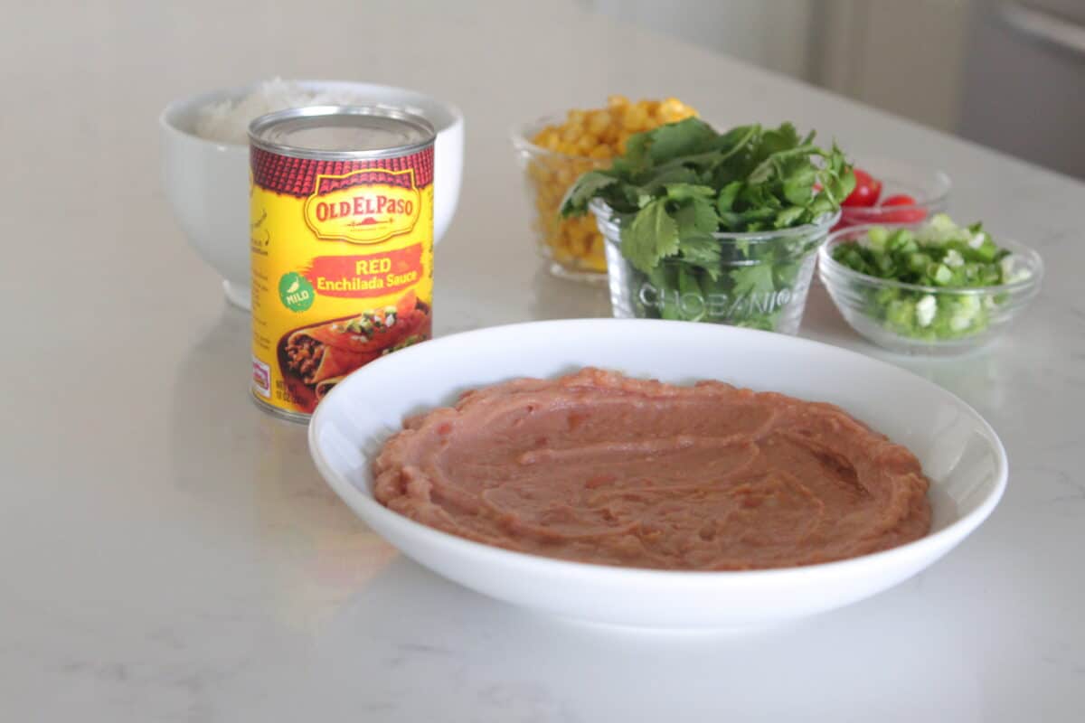 refried beans layered on the bottom of a serving bowl