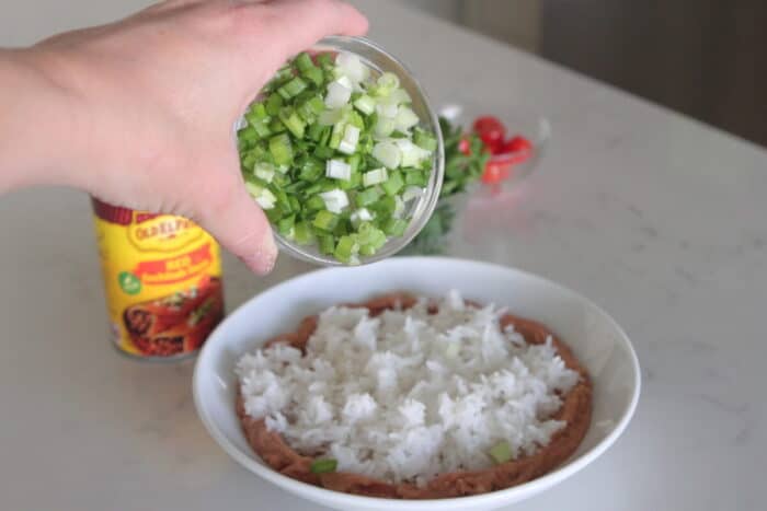 adding green onion to enchilada bowls