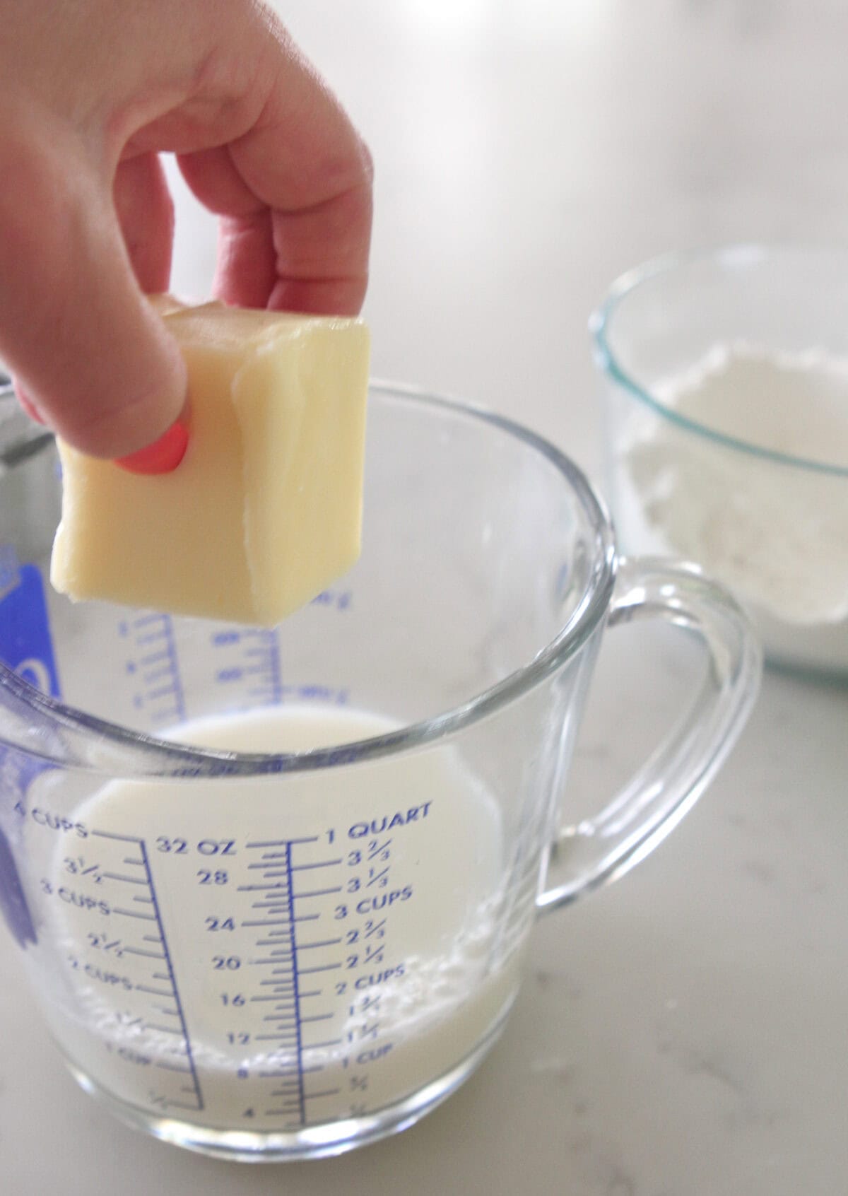 adding butter to milk in a measuring cup to melt