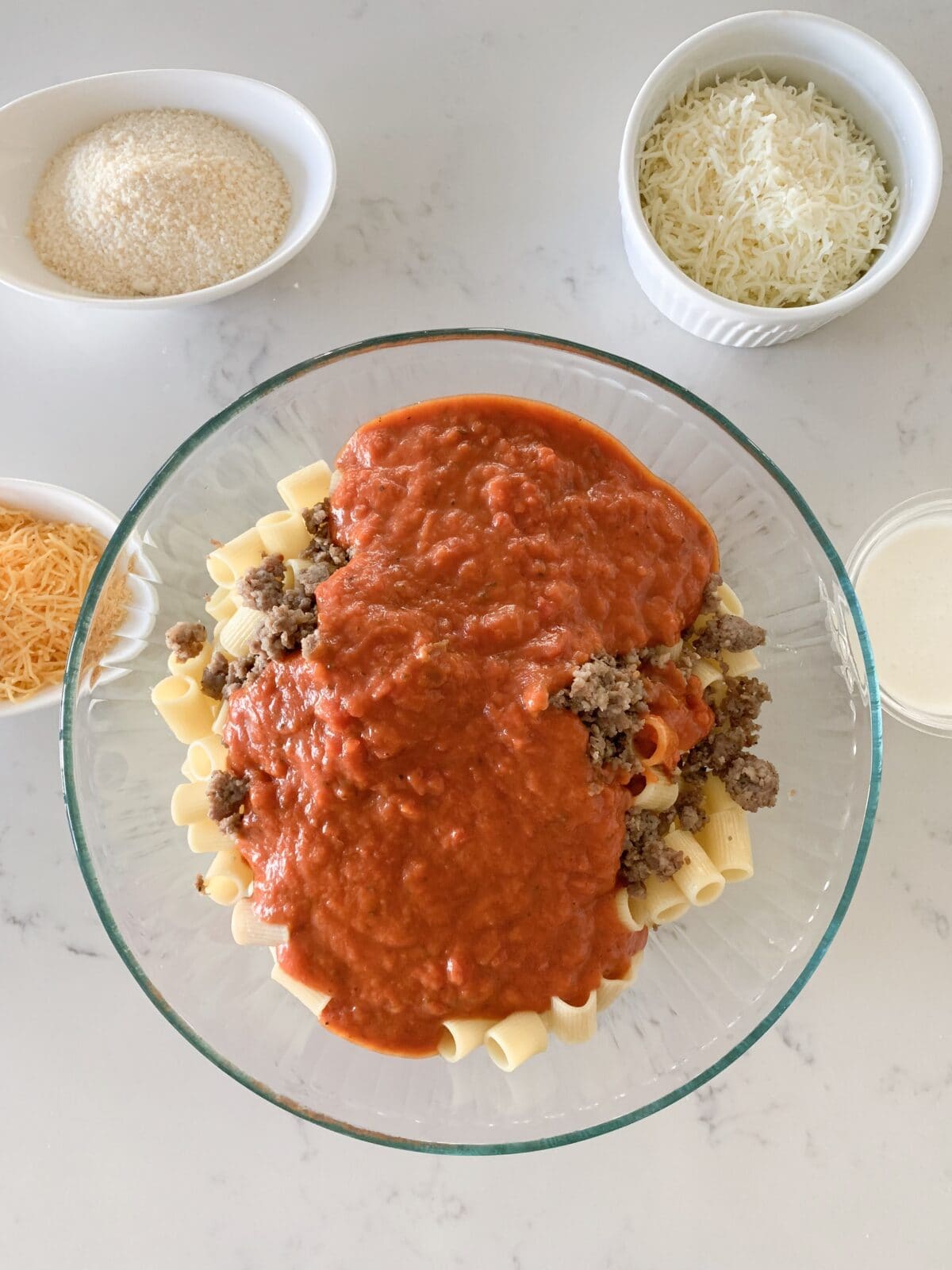 pasta sauce added to large bowl of pasta