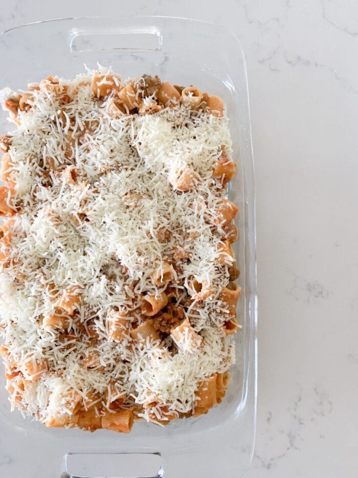 parmesan cheese added to rigatoni in baking dish