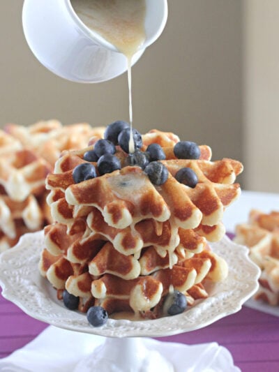 pouring syrup over homemade waffles