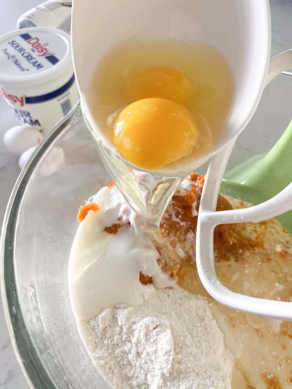 adding eggs to mixing bowl
