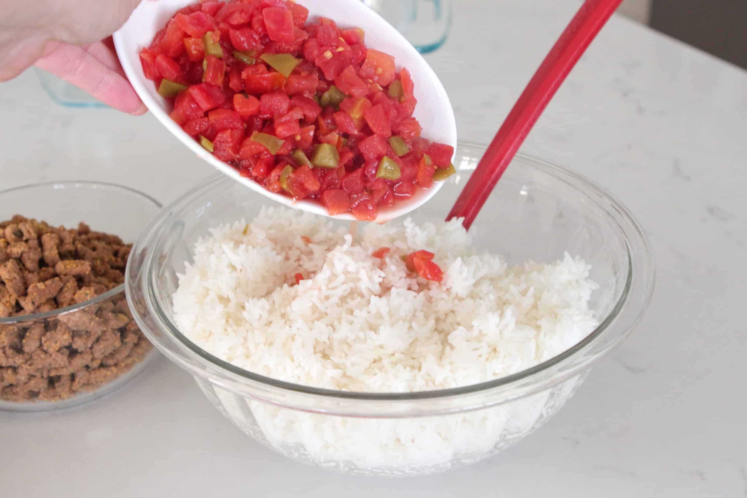 adding diced tomatoes to bowl of cooked rice width=