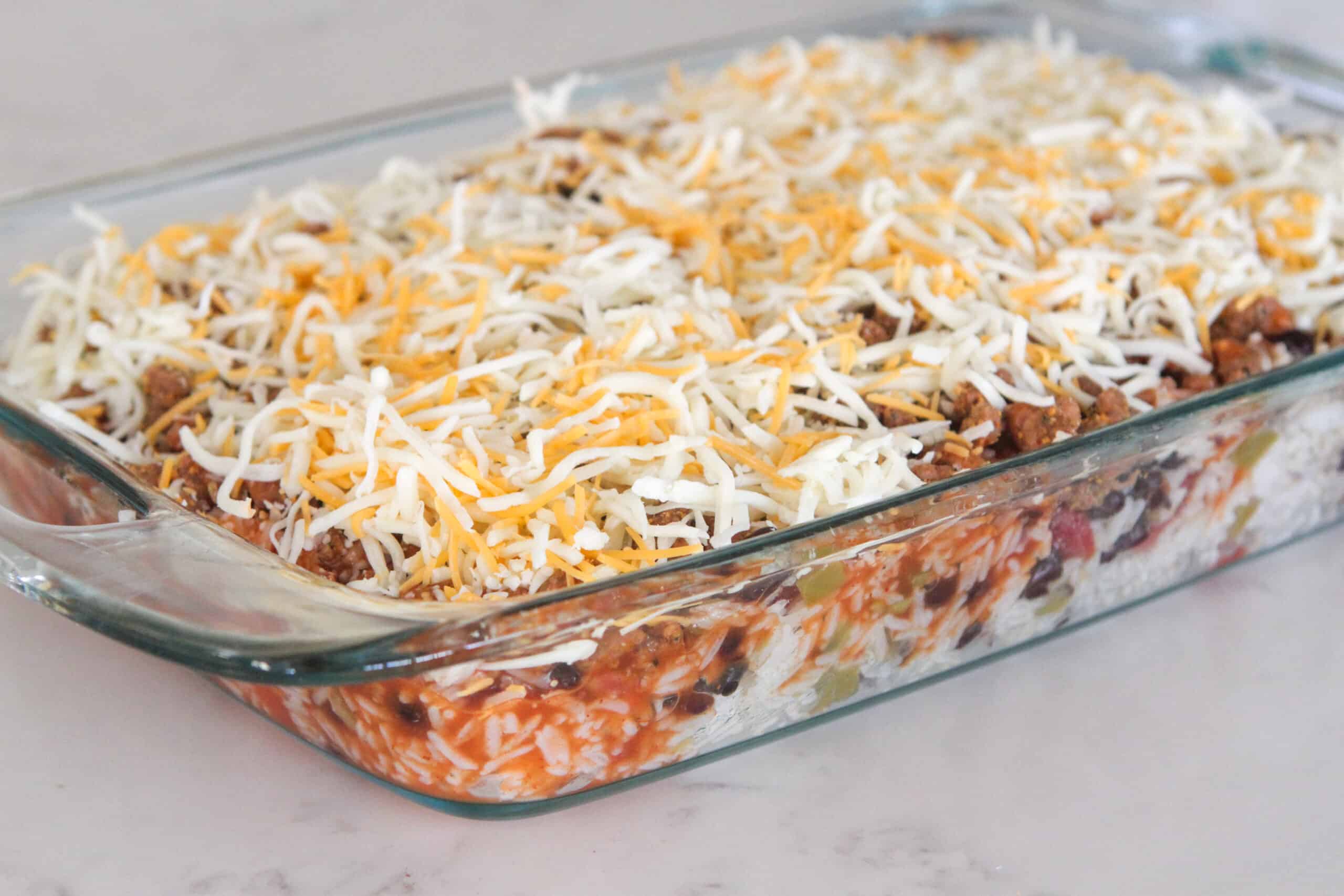 shredded cheese on top of beef enchilada casserole