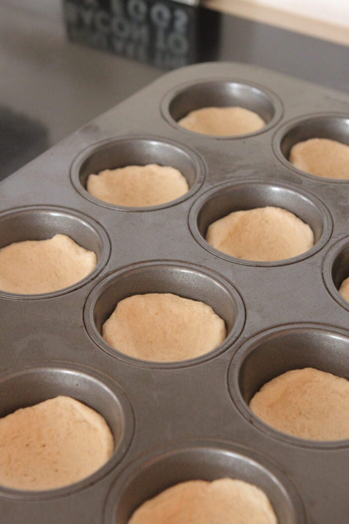bread dough pressed into muffin tin